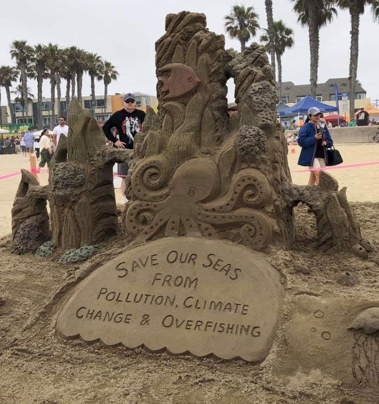 A sand sculpture at a beach with a message: 