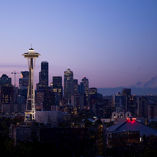 This image shows the Seattle skyline at dusk, highlighting the Space Needle with Mount Rainier in the background.